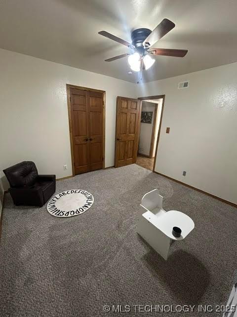 interior space featuring visible vents, carpet flooring, baseboards, and ceiling fan