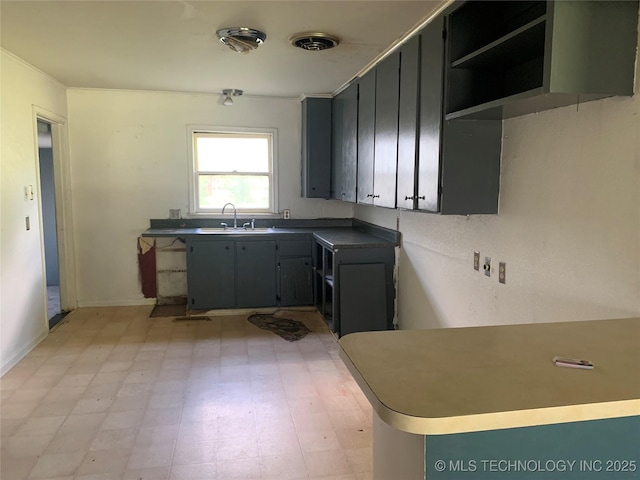 kitchen with baseboards, a sink, light floors, and visible vents