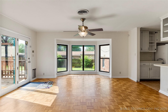 unfurnished dining area with baseboards, visible vents, ornamental molding, and ceiling fan