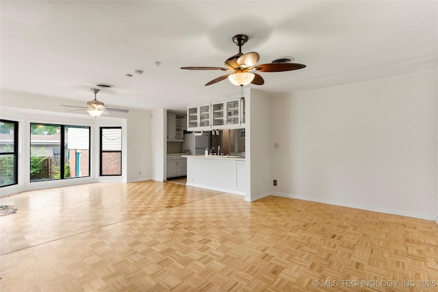 unfurnished living room with baseboards and ceiling fan
