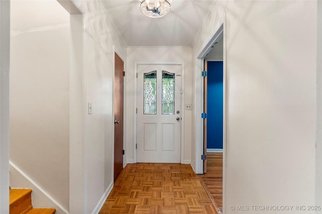 entryway with crown molding, baseboards, and stairway
