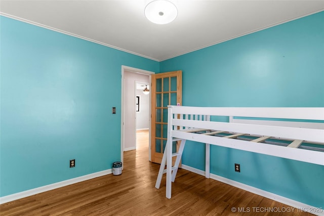 bedroom featuring baseboards, ornamental molding, and wood finished floors