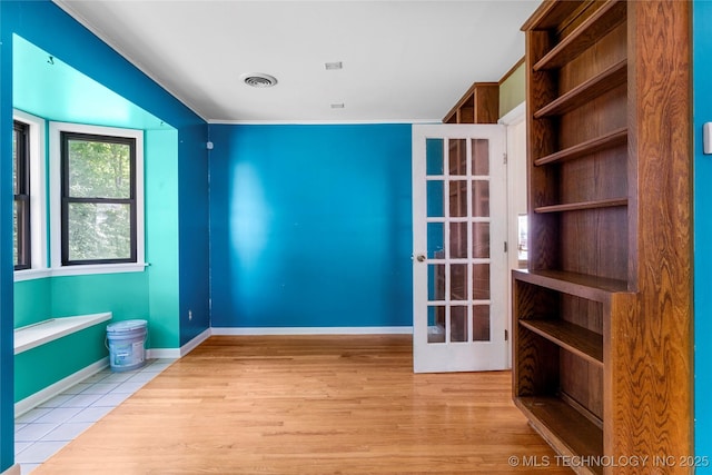 unfurnished room with baseboards, wood finished floors, and visible vents