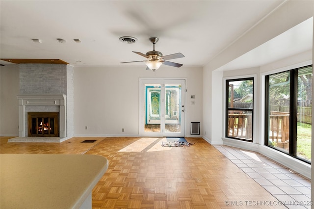 unfurnished living room featuring a brick fireplace, ceiling fan, visible vents, and baseboards
