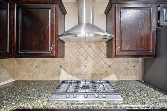 9888 E 470th Rd, Claremore, OK 74017 - kitchen with wall chimney range hood, backsplash, stainless steel gas cooktop, dark brown cabinets, and dark stone counters