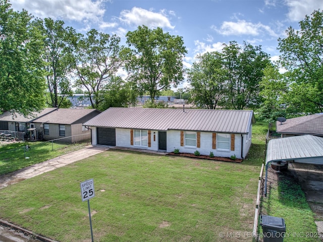 ranch-style house featuring fence, a front yard, metal roof, an attached garage, and driveway