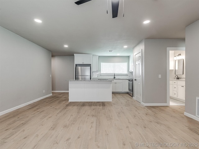 kitchen with white cabinets, ceiling fan, a sink, stainless steel appliances, and baseboards