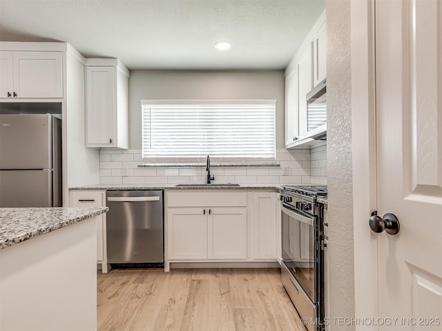 kitchen featuring backsplash, white cabinetry, appliances with stainless steel finishes, and a sink