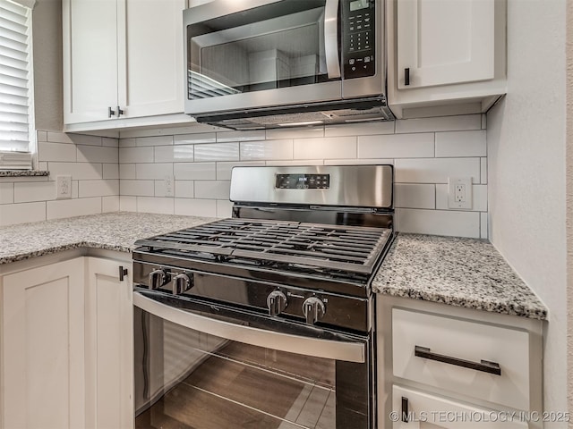 kitchen featuring appliances with stainless steel finishes, decorative backsplash, light stone countertops, and white cabinets