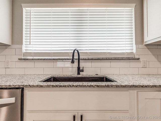 interior details featuring a sink, white cabinetry, backsplash, stainless steel dishwasher, and an outdoor fire pit
