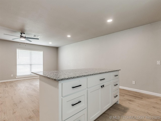 kitchen featuring visible vents, ceiling fan, a center island, white cabinets, and light wood finished floors