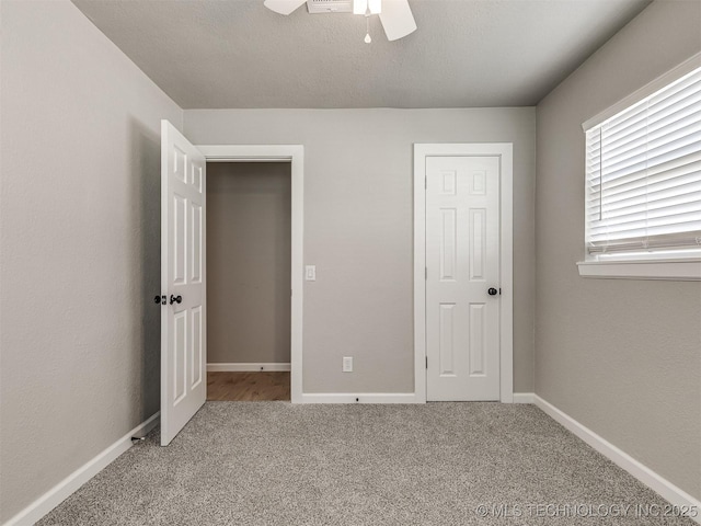 unfurnished bedroom with carpet flooring, a ceiling fan, and baseboards