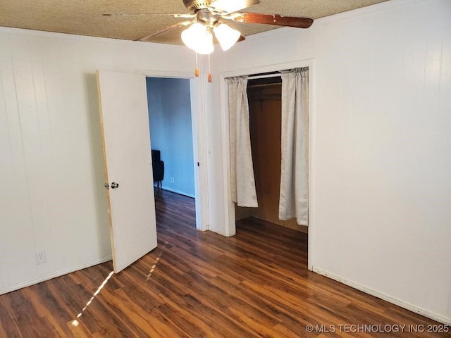 824 W Houston St, Okemah, OK 74859 - unfurnished bedroom featuring dark wood-style flooring, ceiling fan, and a closet