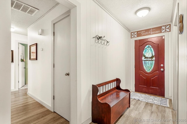 foyer featuring crown molding, a textured ceiling, visible vents, and light wood finished floors