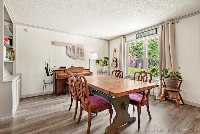 dining area with light wood-style floors, baseboards, and a textured ceiling