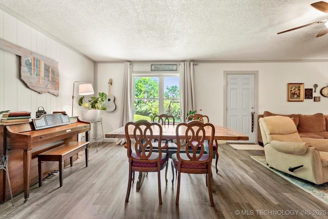 dining area with a ceiling fan, a textured ceiling, and wood finished floors