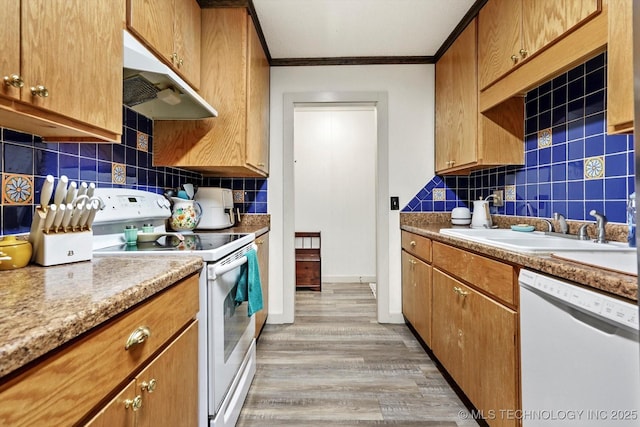 kitchen with white appliances, under cabinet range hood, tasteful backsplash, a sink, and light wood finished floors