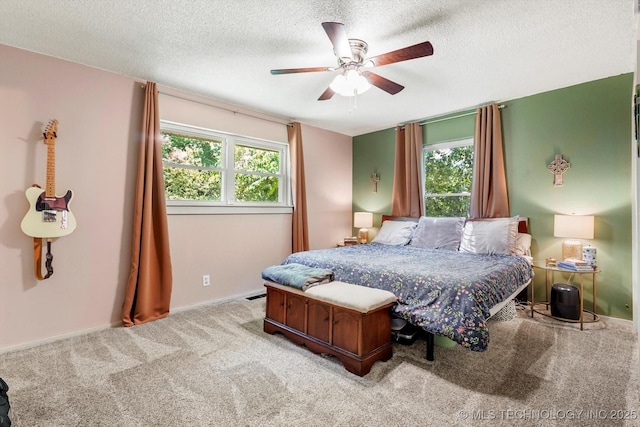 carpeted bedroom featuring baseboards, a ceiling fan, a textured ceiling, and multiple windows