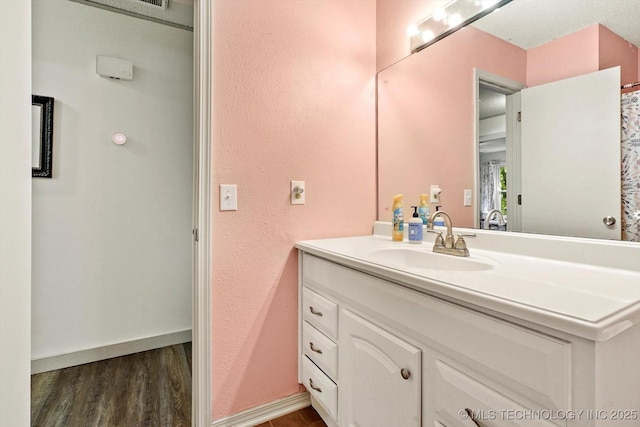 bathroom featuring vanity, baseboards, a textured wall, and wood finished floors