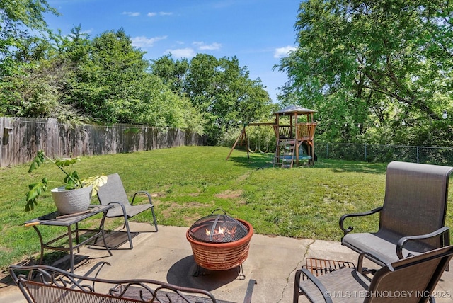 view of yard featuring a patio, a playground, an outdoor fire pit, and a fenced backyard