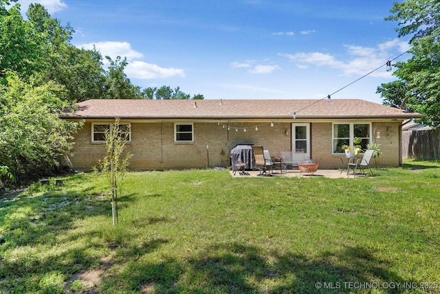 rear view of house with a lawn, a patio area, and brick siding