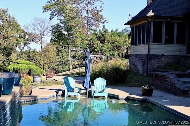 outdoor pool with fence, a patio area, and a sunroom