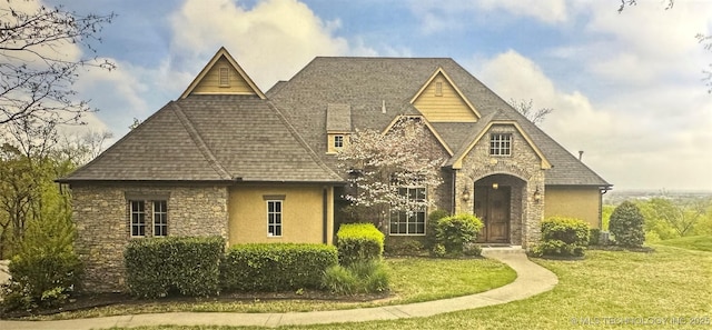 view of front of property with stucco siding, roof with shingles, stone siding, and a front lawn