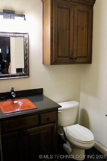 half bathroom with toilet, baseboards, and vanity