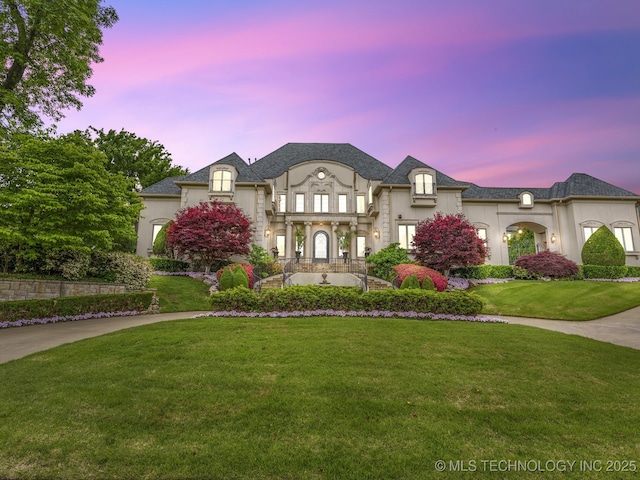 french provincial home featuring a lawn and stucco siding