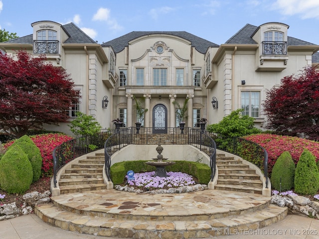 french country home with stairs and stucco siding