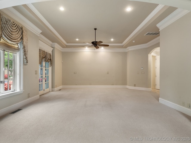 empty room featuring visible vents, arched walkways, ceiling fan, and a tray ceiling