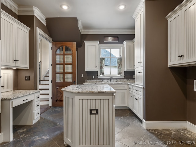 kitchen featuring crown molding, a kitchen island, light stone countertops, recessed lighting, and a sink
