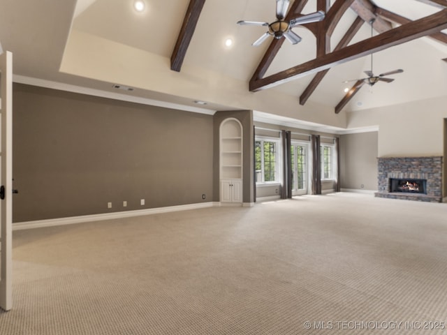 unfurnished living room featuring carpet floors, baseboards, beam ceiling, and a stone fireplace