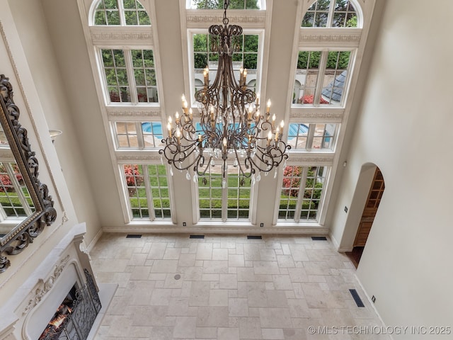 interior space featuring baseboards, stone tile floors, a high ceiling, and a chandelier