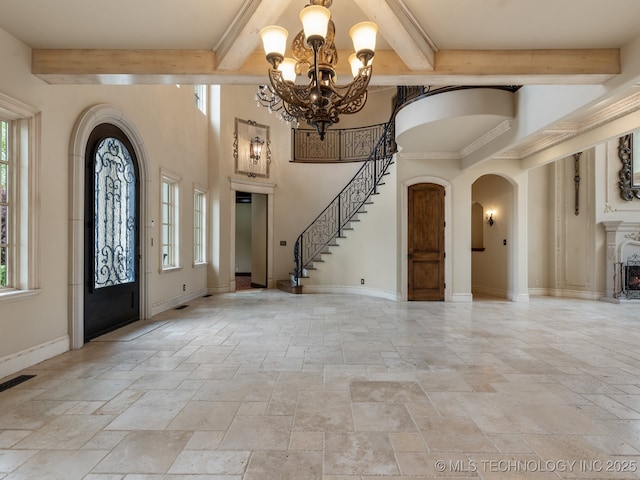 foyer entrance featuring arched walkways, beam ceiling, stone tile flooring, and a wealth of natural light