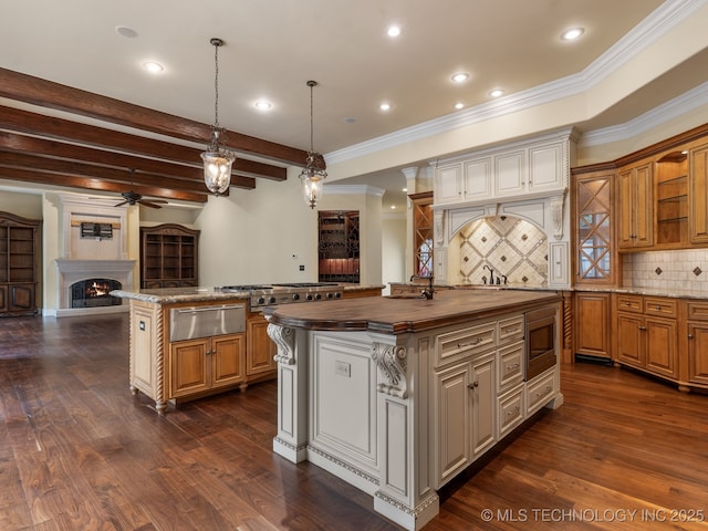 kitchen featuring ceiling fan, a warming drawer, a center island, a warm lit fireplace, and wood counters