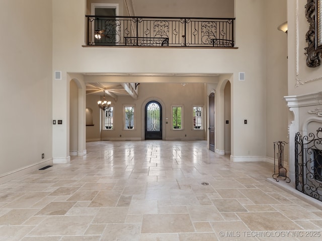 unfurnished living room with arched walkways, a high ceiling, and stone tile flooring