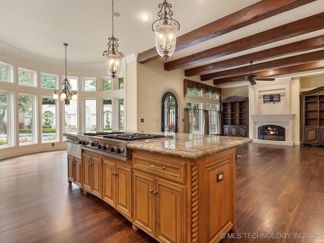kitchen with dark wood-style flooring, a warm lit fireplace, ceiling fan with notable chandelier, decorative light fixtures, and stainless steel gas stovetop