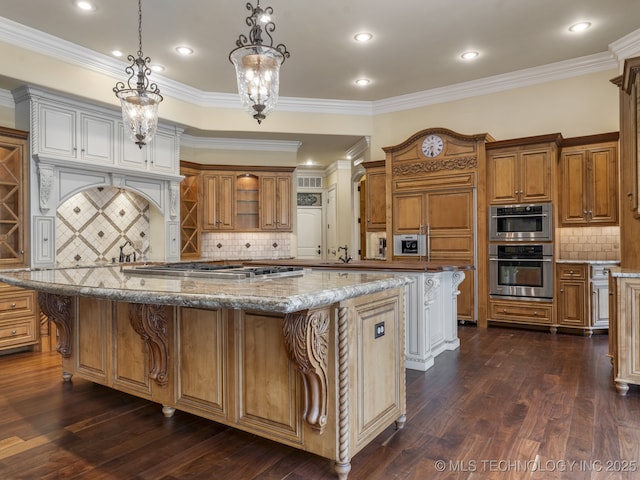 kitchen with appliances with stainless steel finishes, tasteful backsplash, brown cabinetry, and a kitchen island