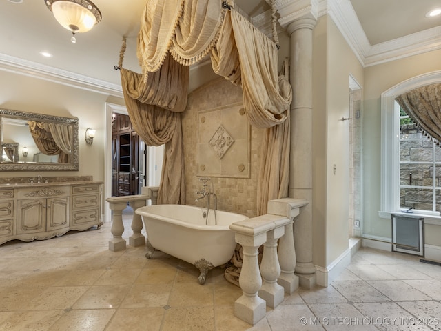 bathroom with a freestanding tub, baseboards, vanity, stone tile flooring, and ornamental molding