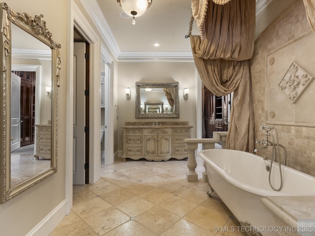 full bathroom featuring crown molding, stone tile floors, vanity, baseboards, and a freestanding bath