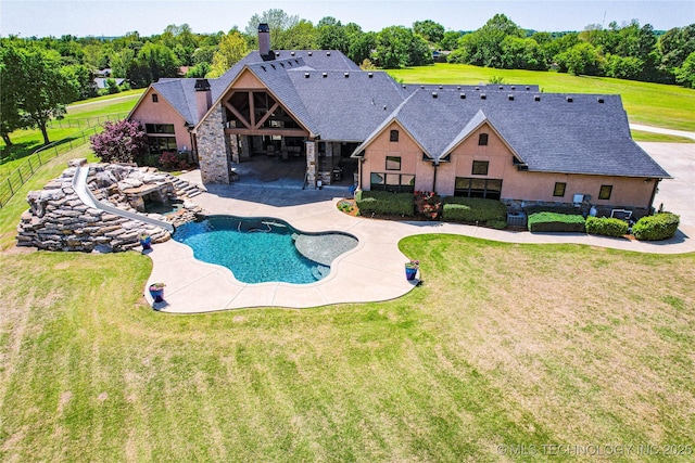 outdoor pool featuring fence, a water slide, a yard, and a patio