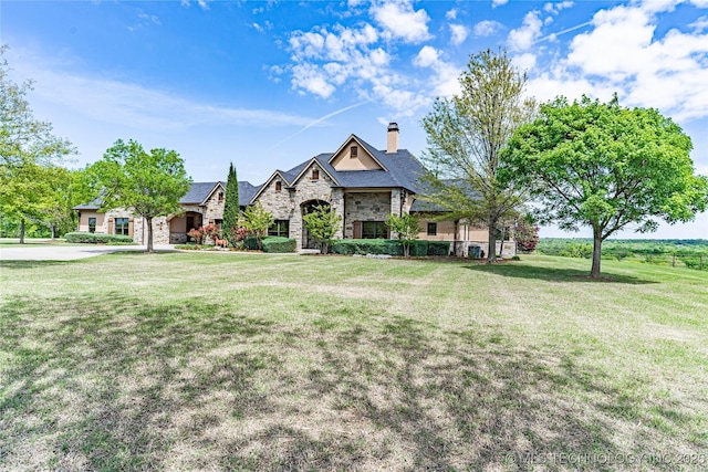 view of front of home featuring a chimney, a front yard, and stone siding