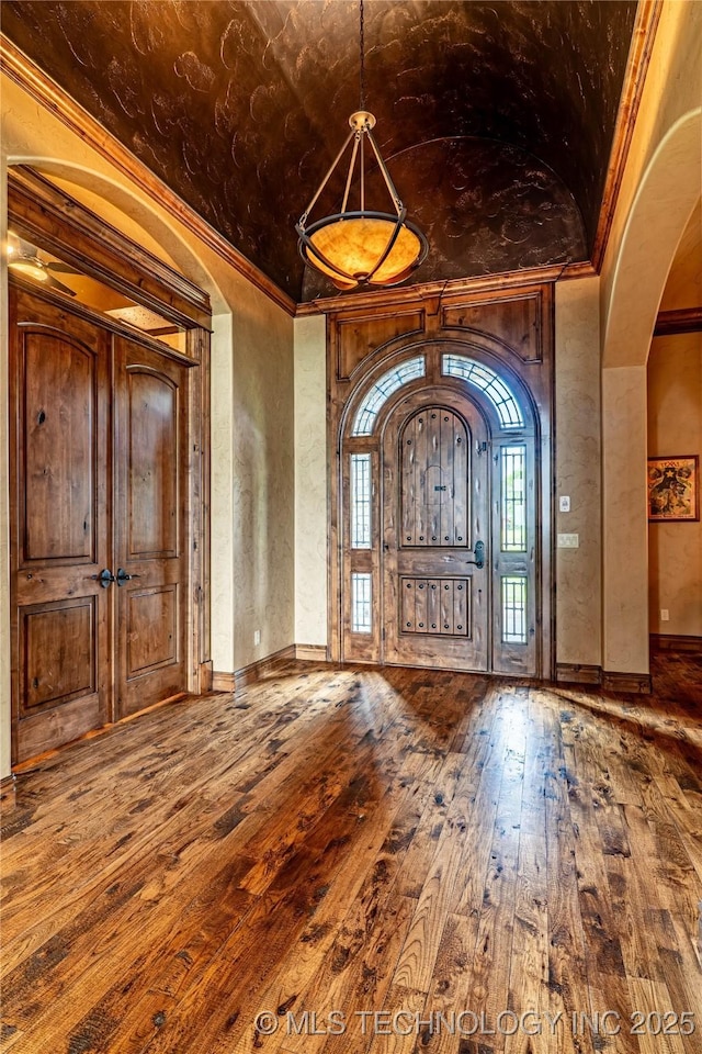 entryway with baseboards, arched walkways, hardwood / wood-style floors, and ornamental molding