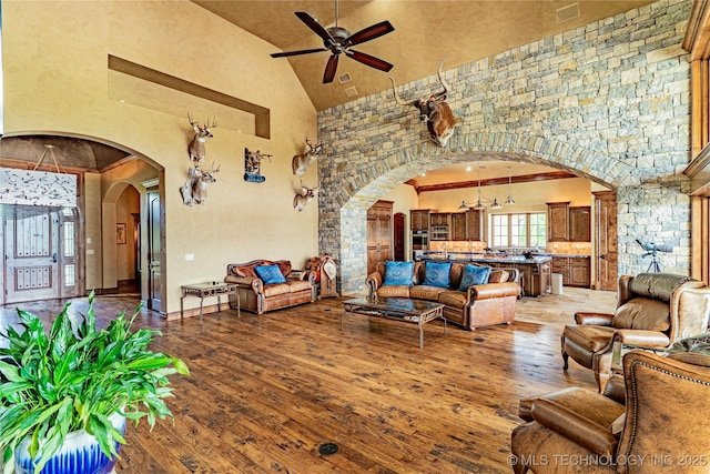 living area featuring arched walkways, ceiling fan, hardwood / wood-style flooring, and high vaulted ceiling