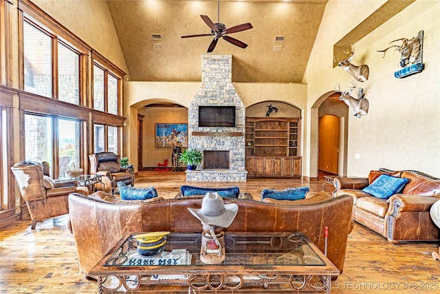 living room with wood-type flooring, arched walkways, and high vaulted ceiling