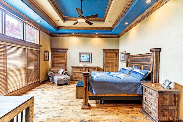 bedroom with crown molding, a high ceiling, a tray ceiling, and wood finished floors