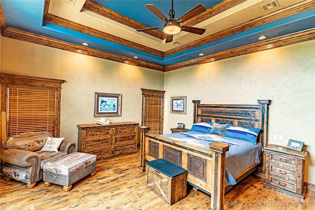 bedroom featuring a raised ceiling, ornamental molding, hardwood / wood-style floors, and visible vents