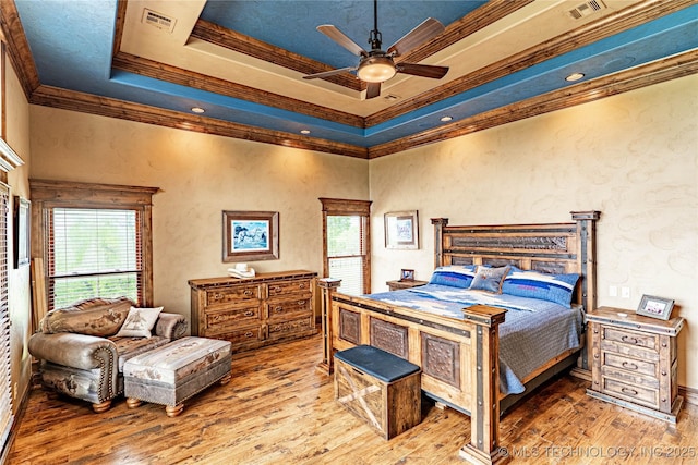 bedroom with crown molding, a tray ceiling, visible vents, and hardwood / wood-style floors