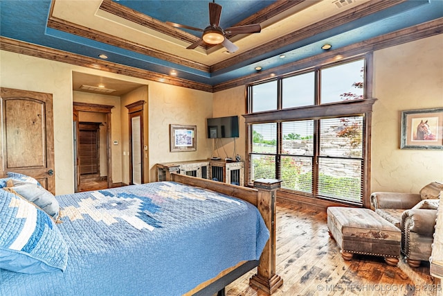 bedroom with ornamental molding, a textured wall, recessed lighting, a tray ceiling, and hardwood / wood-style flooring